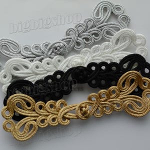 May include: Four decorative fabric closures in silver, white, black, and gold. The closures are made of braided fabric and have a floral design.