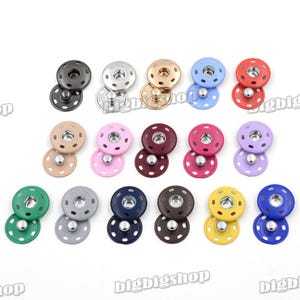 May include: A collection of colorful snap fasteners in various shades, including black, silver, gold, blue, red, pink, burgundy, purple, green, gray, navy, brown, yellow, and royal blue. Each snap consists of two pieces, a top and a bottom.