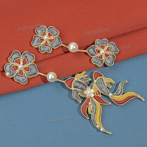 May include: Gold-toned floral and bow-shaped earrings with pearl accents. The earrings feature blue, red, and yellow enamel detailing. The design includes flower and bow shapes, with a pearl at the center of each.
