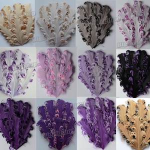 Puede incluir: Una colección de plumas decorativas en varios colores, incluyendo beige, blanco, gris, morado y negro. Cada pluma tiene un diseño rizado único. Las plumas están dispuestas en forma de abanico, adecuadas para manualidades y adornos.