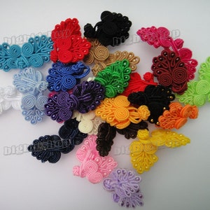 May include: Assortment of colourful Chinese knot buttons in various shapes and sizes. The buttons are made of braided cord and feature decorative beads.