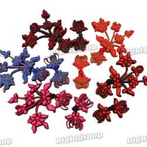 May include: Assortment of colorful Chinese knot embellishments in red, pink, blue, and gold. The knots are in the shape of flowers and branches.