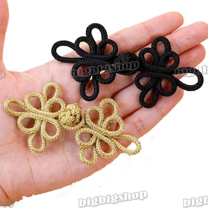 Op de afbeelding: Twee paar decoratieve Chinese knoopknoppen. Het ene paar is zwart en het andere is goud.