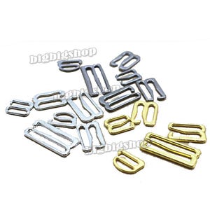 May include: A collection of metal bra strap adjusters in gold, silver, and black.