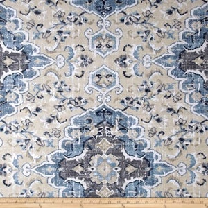 May include: Close-up of a fabric with a distressed, vintage-style pattern. The design features a repeating floral and geometric motif in shades of beige, blue, and brown. The fabric is likely used for upholstery or home decor.
