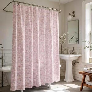 May include: A pink and white patterned shower curtain hangs in a bathroom. The curtain features a repeating circular design. The bathroom has a white pedestal sink, a mirror, and a bathtub.