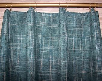 May include: Teal-colored curtain with a plaid pattern. The curtain is hanging from a gold-colored rod with silver rings. The plaid design features thin white lines over the teal fabric. The curtain is made of a textured material.