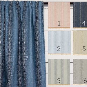 May include: A close-up of a blue curtain with a white dot pattern. The curtain is hanging on a white wooden wall. There are six smaller swatches of fabric in different colors and patterns below the curtain, numbered 1 through 6.