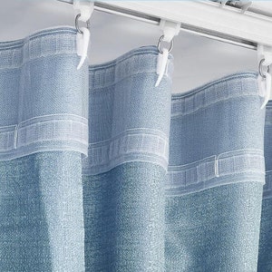 May include: Blue curtains with a white sheer lining, hanging from a white track with silver hooks.