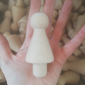 May include: A wooden doll with a round head and a skirt-like body. The doll is made of unfinished wood and has a smooth surface.