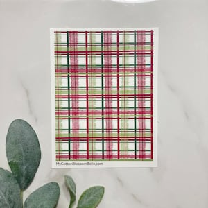 May include: A rectangular card with a plaid pattern in red, green, and white. The plaid design features thick, brushstroke-style lines. The text "MyCottonBlossomBelle.com" is printed at the bottom of the card.