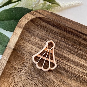 May include: A light pink plastic cookie cutter shaped like a badminton shuttlecock.