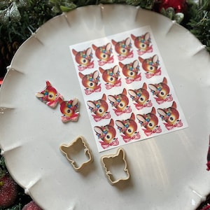 May include: A white plate with a sheet of 16 vintage Christmas deer stickers, two deer cookie cutters, and two hand-painted deer ornaments.