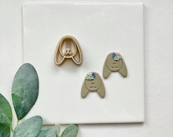 May include: A set of two brown bunny cookie cutters with a floral design. One cutter is a solid bunny head and the other is a bunny head with ears.