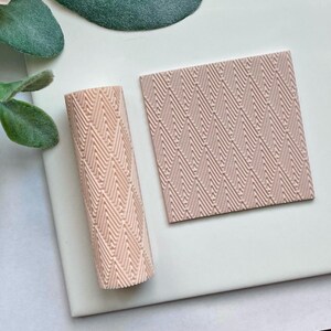 May include: A set of two pink silicone embossing mats with a chevron pattern. The mats are designed for use with fondant, gum paste, and other edible materials.