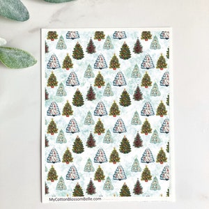May include: A rectangular card featuring a repeating pattern of Christmas trees in various colors, including green, red, and white, set against a light blue and white background. The text "MyCottonBlossomBelle.com" is visible at the bottom.