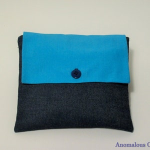 May include: A small blue and denim pouch with a blue button closure.