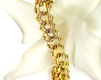 May include: A gold-toned bracelet with a chain link design. The links are interlocked and have a textured finish. The bracelet is about 7 inches long.