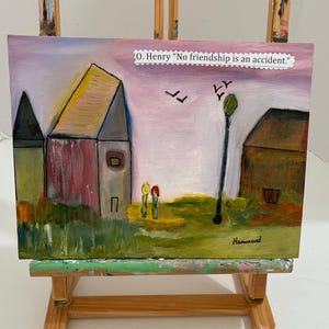 May include: An original painting on canvas, displayed on a wooden easel. The artwork depicts a whimsical landscape with buildings, figures, and a street lamp. The text "O. Henry 'No friendship is an accident'" is included.