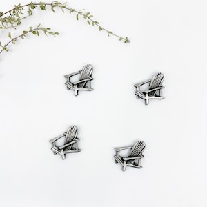 May include: Four miniature silver-colored Adirondack chairs, arranged in a square pattern on a white background.