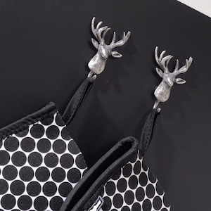 May include: Two silver deer head hooks with black and white polka dot fabric hanging from them.