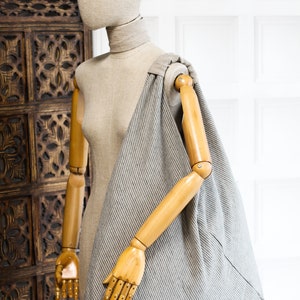 May include: A gray and white striped tote bag with a wooden handle. The bag is hanging on a wooden mannequin.