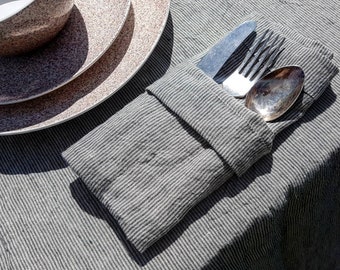 May include: A gray and white striped linen napkin with a silver fork, knife, and spoon folded inside.