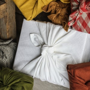 May include: Various fabric gift wrapping techniques using different colors and patterns, including white, green, brown, red, and black.