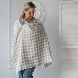 Pu&ograve; includere: Una donna con una camicia bianca e jeans blu sta usando un copriallattamento a quadri beige e bianchi.