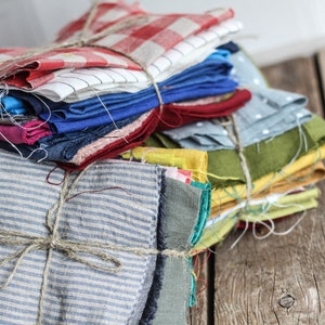 May include: A stack of colorful fabric scraps tied with twine, ready for a quilting project. The fabrics include red, blue, green, yellow, and white.