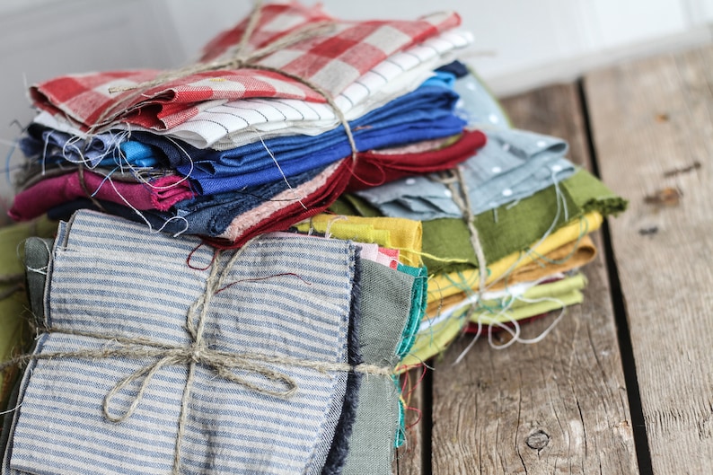 May include: A stack of colorful fabric scraps tied with twine, ready for a quilting project. The fabrics include red, blue, green, yellow, and white.