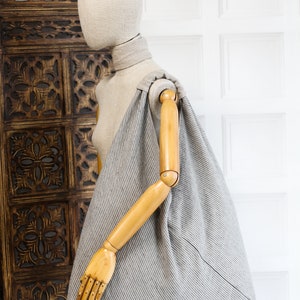 May include: A gray and white striped linen tote bag with a wooden handle. The bag is large and roomy, and it is perfect for carrying everyday essentials.