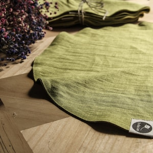 May include: A round, green linen placemat with a small, black and white label that says "friluftsliv".