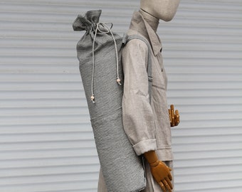 May include: A grey and white striped yoga mat bag with a drawstring closure. The bag is worn by a mannequin wearing a beige linen dress.