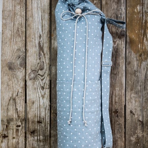 May include: A blue and white polka dot yoga mat bag with a drawstring closure and a long strap. The bag is made of a soft, durable fabric and is perfect for carrying your yoga mat to and from the studio.