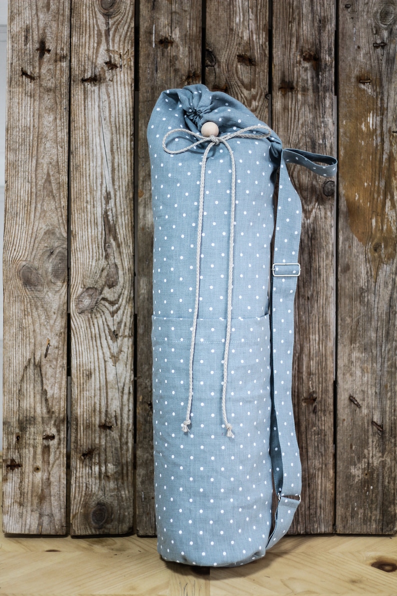 May include: A blue and white polka dot yoga mat bag with a drawstring closure and a long strap. The bag is made of a soft, durable fabric and is perfect for carrying your yoga mat to and from the studio.