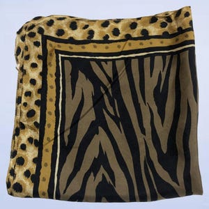 May include: A square scarf featuring a central panel with a black and brown zebra stripe pattern, bordered by a thin cream line, a solid mustard yellow band with small brown dots, and an outer edge with a brown and black leopard print design.