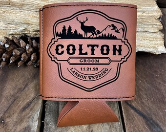 May include: Brown leather can cooler with a black silhouette of a deer and trees. The text "COLTON GROOM 11.21.23 LARSON WEDDING" is engraved on the cooler.
