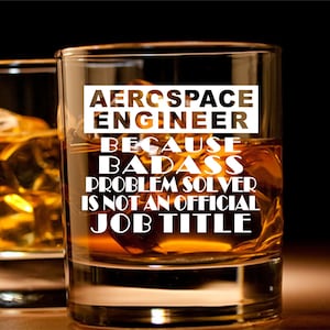 May include: A glass of amber liquid in a rocks glass with the text "Aerospace Engineer Because Badass Problem Solver Is Not An Official Job Title" printed on the glass.
