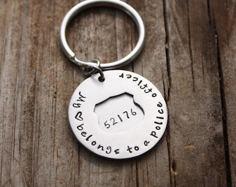 May include: Silver keychain with a police badge cutout and the text "My ♥ belongs to a Police Officer".