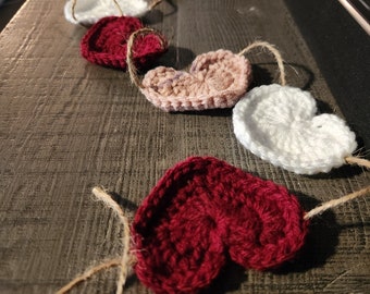 May include: A garland of crocheted hearts in red, white, and pink, strung together with twine.