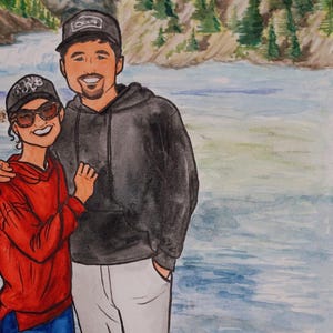 May include: A watercolor painting of a couple standing in front of a river. The man is wearing a black hoodie and a black baseball cap. The woman is wearing a red hoodie and a black baseball cap. The river is blue and green and there are trees in the background.