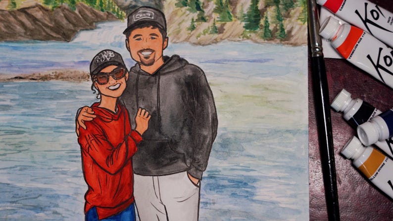 May include: A watercolor painting of a couple standing in front of a river. The man is wearing a black hoodie and a black baseball cap. The woman is wearing a red hoodie and a black baseball cap. The river is blue and green and there are trees in the background.