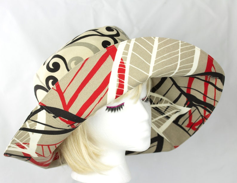 Reversible Summer hat with very wide brim. Abstract print pattern with black, red and white on a beige background. The reverse side has black and grey swirls on a light beige background. Sewn from cotton duck which is slightly waterproof.