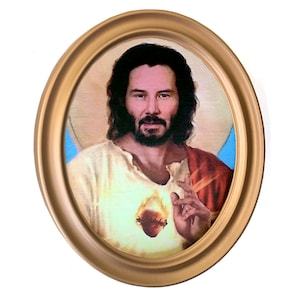 May include: A framed painting of a man with long dark hair and a beard, wearing a white robe and a red sash. He has a glowing heart in his chest and is holding his hand up in a gesture of blessing.