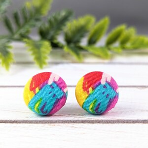 May include: A pair of colourful fabric earrings with a blue, yellow, pink and red abstract pattern.