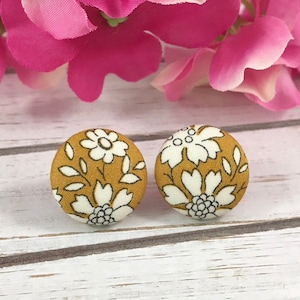 May include: A pair of mustard yellow fabric earrings with a white floral pattern.