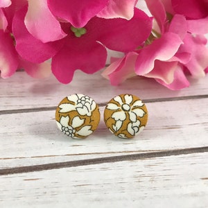 May include: A pair of mustard yellow fabric earrings with a white floral pattern.