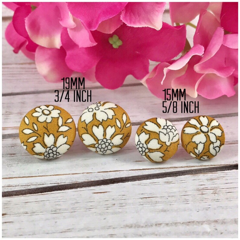 May include: Four fabric covered buttons in two sizes. The larger buttons are 3/4 inch (19 mm) and the smaller buttons are 5/8 inch (15 mm). The buttons have a mustard yellow background with a white floral pattern.