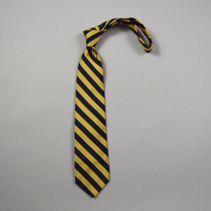 May include: A necktie featuring a repeating diagonal striped pattern in navy blue and golden yellow. The tie is tied in a knot at the top, with the fabric folded over to form a loop. The material has a smooth, slightly reflective finish throughout.
